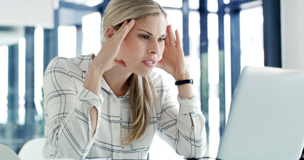 一个女商人在现代办公室里带着压力和头痛使用笔记本电脑。一位在线工作的女商人，在办公桌前感到疲惫不堪图片下载