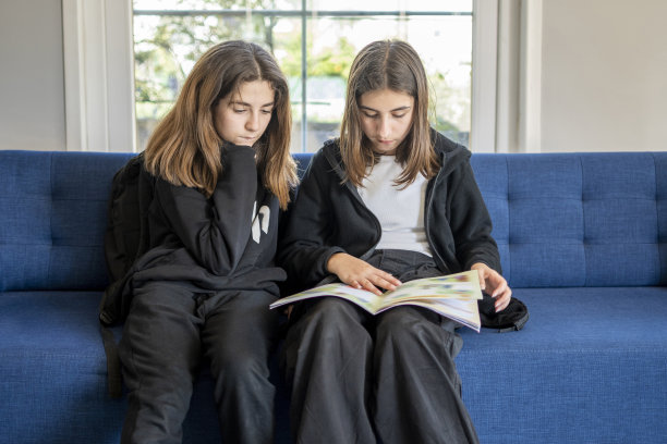 漂亮的女孩坐在家里的沙发上看书图片下载