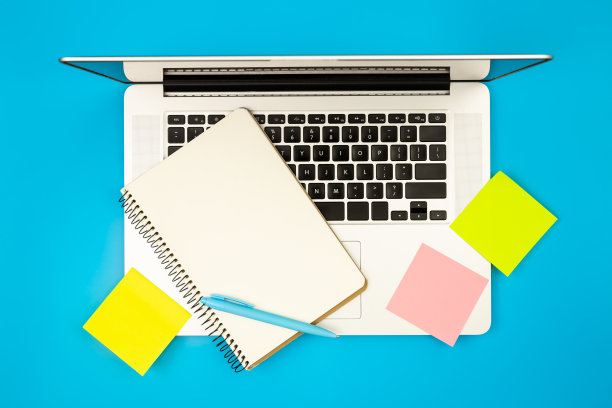 笔记本电脑，记事本和纸质提醒，蓝色背景，平放。图片下载