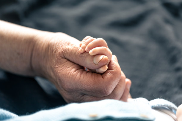 老人和小婴儿的手靠近。图片下载