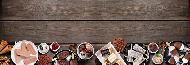 凉爽的夏季巧克力冰淇淋和冷冻治疗底部边界在黑暗的木材背景图片下载