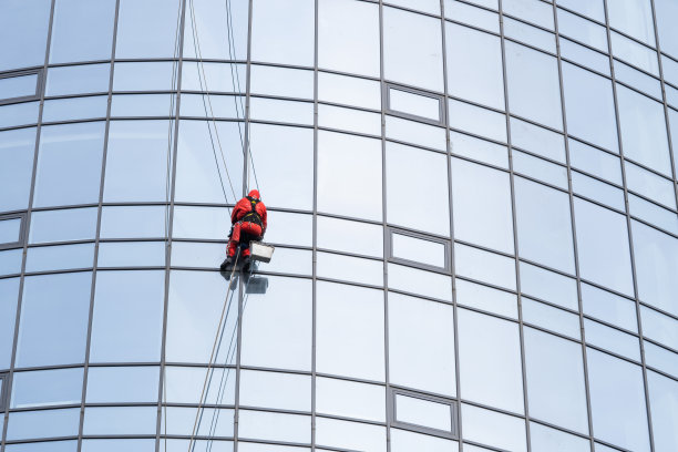 一名工人正在清洁一栋现代建筑的窗户。图片下载