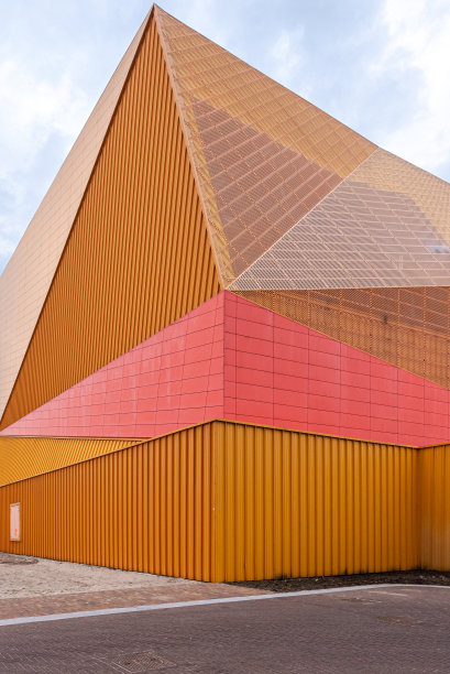 一个公共建筑的抽象抬头照片，橙色和红色的色调和干净的线条，蓝色的天空图片下载