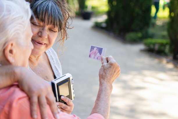 老妇人与大女儿用模拟即时相机一起在纸上拍全家福。女人手里拿着家庭自拍。概念微笑与爱图片下载