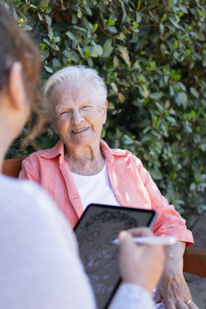 度假时，母亲和女儿微笑着用她的数码平板电脑和电子铅笔画了一幅漫画肖像。趣味和艺术概念。滑稽的场景。鬼混和傻乎乎的鬼脸。图片下载