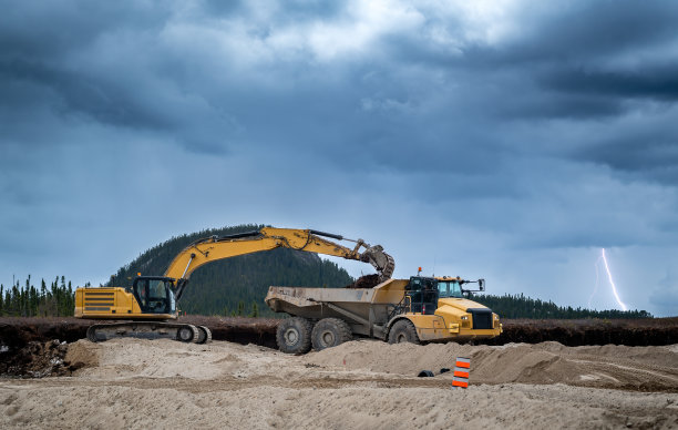 挖掘机和翻车机与暴风雨的天空图片下载