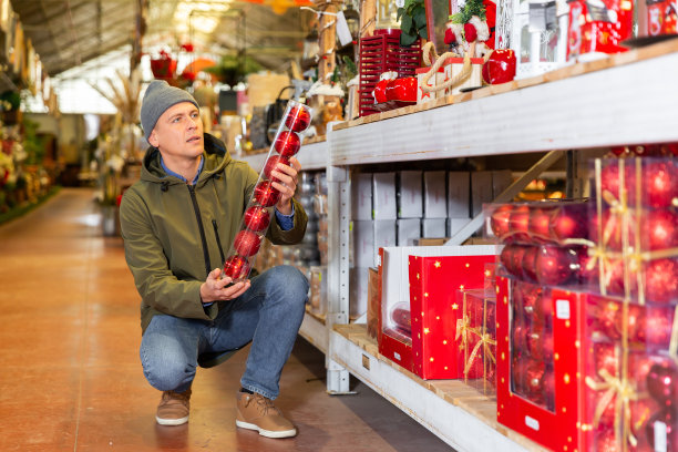 为新年做准备——快乐的人在商店的仓库里挑选圣诞树装饰图片下载