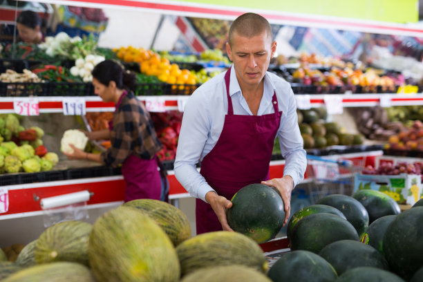 穿围裙的男人站在蔬菜水果店图片下载
