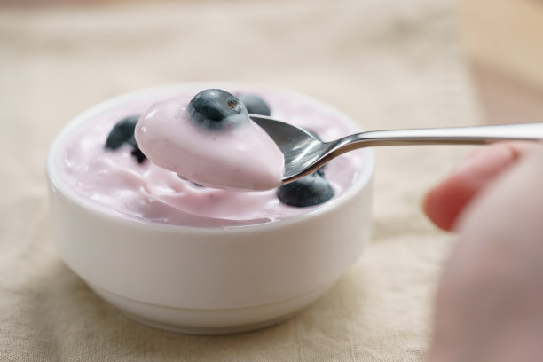 一个十几岁的女孩用手吃着有机蓝莓酸奶图片下载