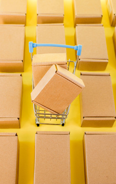 黄色背景上有盒子的购物车。销售、折扣、网上购物和送货的概念。图片下载