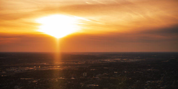 刺眼的金色阳光照耀在夕阳下的天空。图片下载