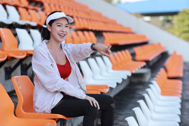 图为快乐而兴奋的亚洲年轻女体育迷，她坐在体育场的空座位中，为获胜的球队欢呼并鼓掌观看比赛图片下载