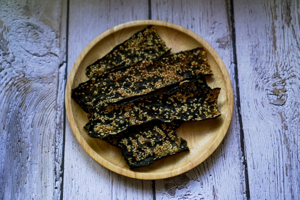 一张俯视图照片显示，脆皮海藻和白芝麻混合在一起，排列在一个木制餐具上。图片下载