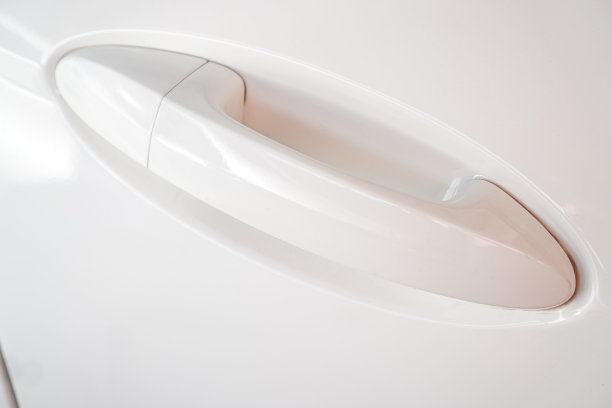 图为一辆城市轿车驾驶员侧后门上的白色门把手。图片下载