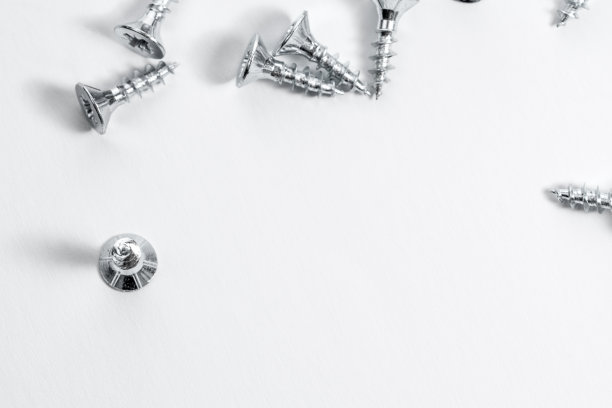 一堆螺丝躺在白色的表面上。图片下载