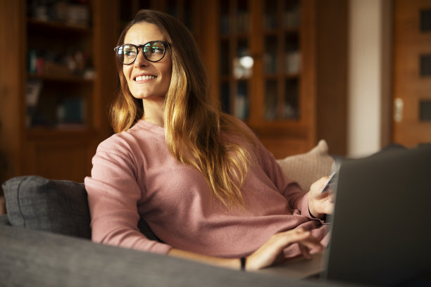 年轻女子在家里用信用卡和笔记本电脑。图片下载