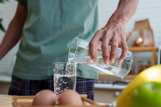 一个亚洲人的手在假期的早晨，早餐后把口香糖里的水倒进杯子里喝。清洁牙龈中的饮用水。图片下载