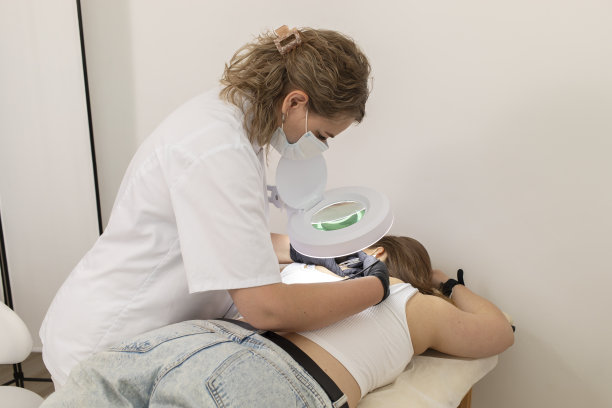 大师用电解法在女性背部脱毛，在美容院用电脱毛。多毛主义的真实照片。水平面图片下载