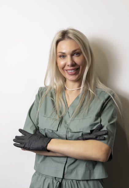 模拟女美容医生，美容医生与Venire牙齿微笑穿着卡其制服，衣服，白色背景上的黑色手套。垂直平面。图片下载