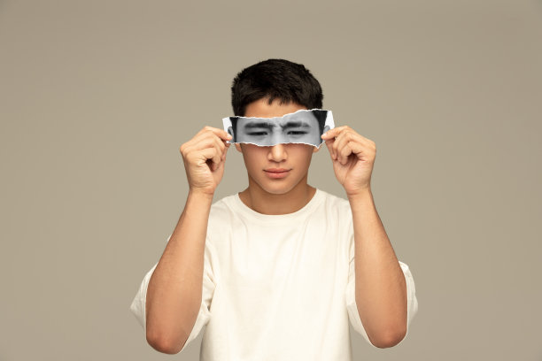 年轻的亚洲男子手持黑白照片片的眼睛表达悲伤的情绪。创造性的拼贴画。图片下载