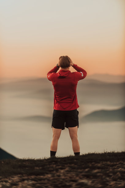 运动员在筋疲力尽的跑步训练后在山顶上休息。图片下载