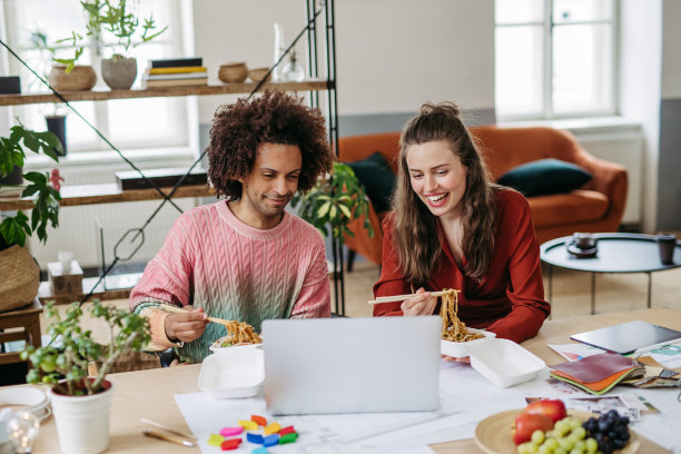 年轻的同事在办公室吃午饭。图片下载