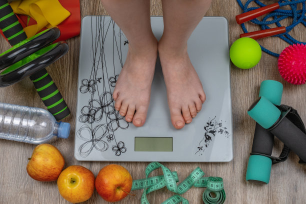 两个孩子的脚放在地板秤上，旁边的地板上是健身器材。儿童健康与运动。儿童与体育。健康生活理念，控制体重图片下载