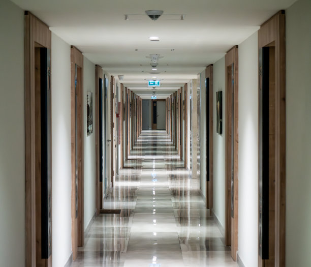 酒店里长长的走廊里有很多门，大窗户里透出亮光图片下载