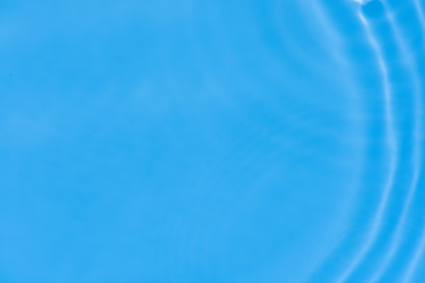 蓝蓝的水面上泛起涟漪。散焦模糊透明蓝色透明平静水面纹理与飞溅和气泡。水波与闪亮的图案纹理背景。图片下载