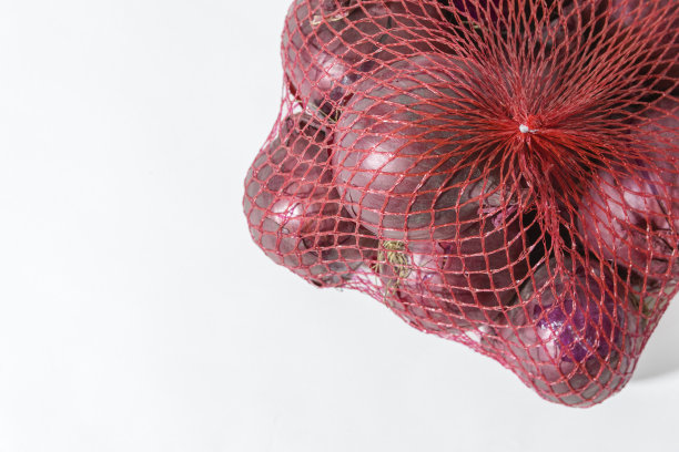 红洋葱在购物塑料网上白色。特写镜头。本空间图片下载