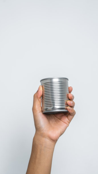 手拿罐头食品孤立在白色，女人的手。图片下载