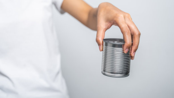 手拿罐头食品孤立在白色，女人的手。图片下载