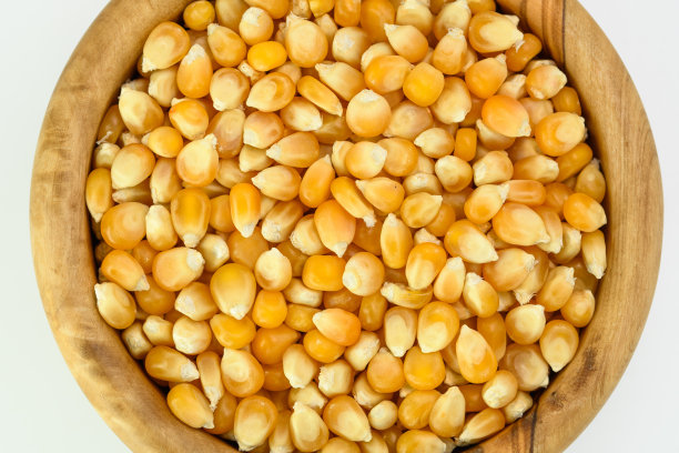 白色背景下木质圆碗里的玉米粒特写图片下载