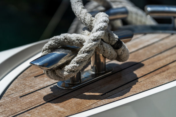 木质甲板上的游艇系泊绳系在不锈钢膝盖上。图片下载