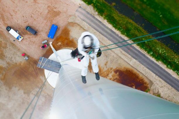 高空作业技师(手工高空作业人员，工业攀爬者)从风力涡轮机上绳下来，并进行塔架和油漆检查。图片下载
