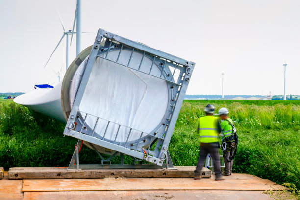 大型风力发电机叶片铺设地面，两名手工高工，技术人员在叶片前工作-站在叶片前检查-准备运输。荷兰风力发电场施工现场。图片下载