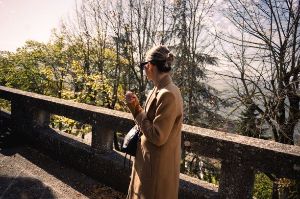 一个女人在阳光明媚的秋日里散步的后景。图片下载