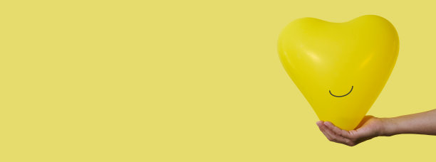 男子手持一个笑脸黄色气球，横幅格式图片下载