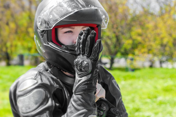 一个戴着摩托车防护头盔的女孩戴上手套图片下载