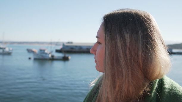 清晨，十几岁的女孩站在码头上，身后是渔船图片下载