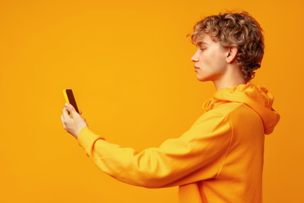 快乐的白人年轻人在黄色背景下使用智能手机图片下载