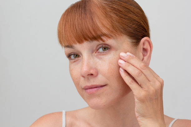 白色背景上，白人中年妇女脸上的雀斑用手触摸皮肤图片下载