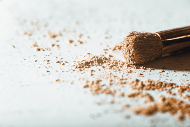 在白色的背景上，用大粉刷在裸色调的粉饼状粉饼。宏,特写图片下载