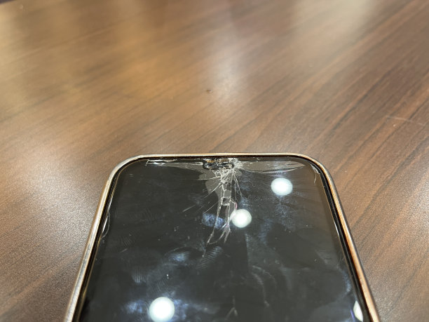 手机屏幕破裂，桌子上有碎玻璃图片下载
