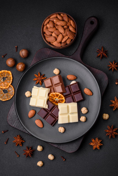 把几种美味的甜巧克力分成小块放在黑色盘子里图片下载