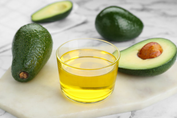 白色大理石桌子上盛着油和新鲜牛油果的碗，特写图片下载