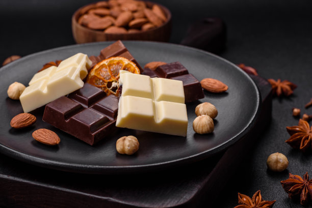 把几种美味的甜巧克力分成小块放在黑色盘子里图片下载