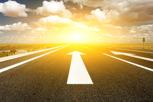 前面的箭头在柏油路和日落的背景图片下载