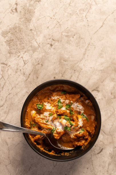 大理石柜台上黑色碗里的黄油鸡配米饭图片下载