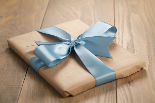 棕色纸礼盒与蓝丝带蝴蝶结在橡木桌上图片下载